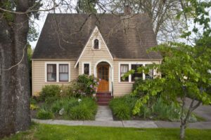 Older clapboard bungalow surrounded by green shrubs